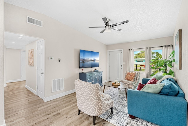 living area with visible vents, light wood-style flooring, baseboards, and a textured ceiling