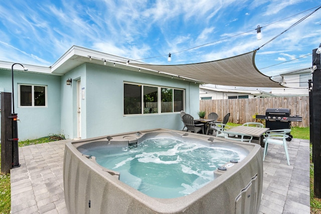 view of patio with a hot tub, fence, and grilling area