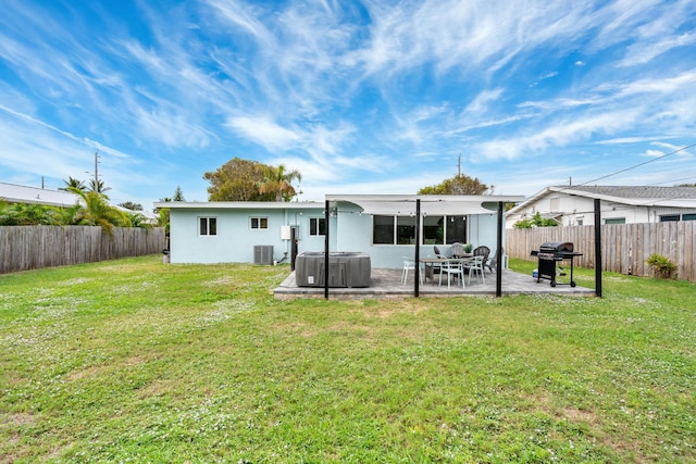 rear view of house with a yard, a fenced backyard, cooling unit, and a hot tub