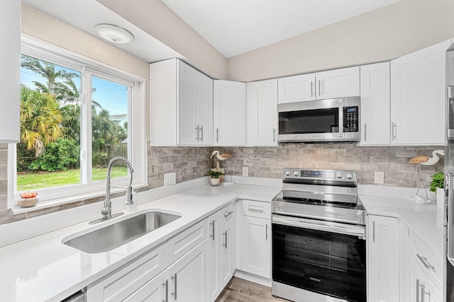 kitchen featuring light countertops, appliances with stainless steel finishes, a sink, and tasteful backsplash