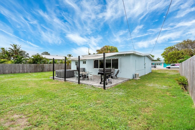 back of property featuring a yard, a patio area, a fenced backyard, and a hot tub