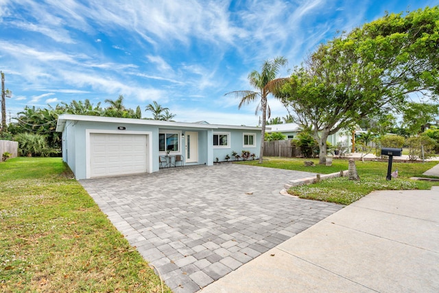 view of front facade featuring a garage, fence, decorative driveway, stucco siding, and a front yard