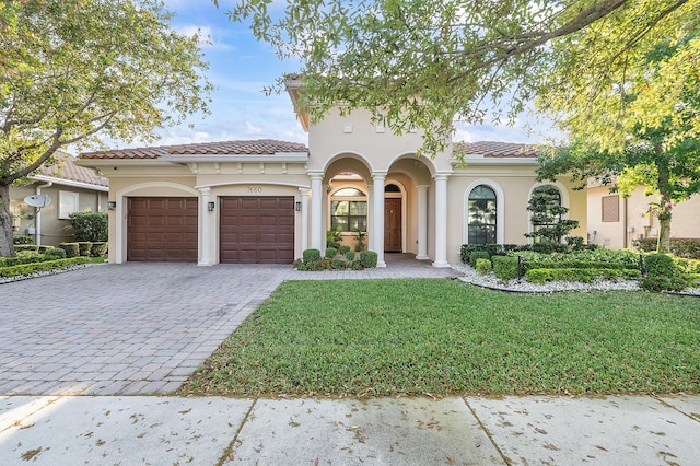 mediterranean / spanish-style home with decorative driveway, a front lawn, an attached garage, and a tile roof