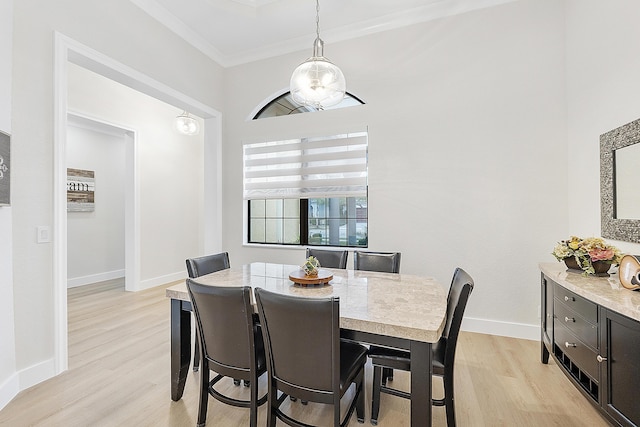 dining area with crown molding, baseboards, and light wood finished floors