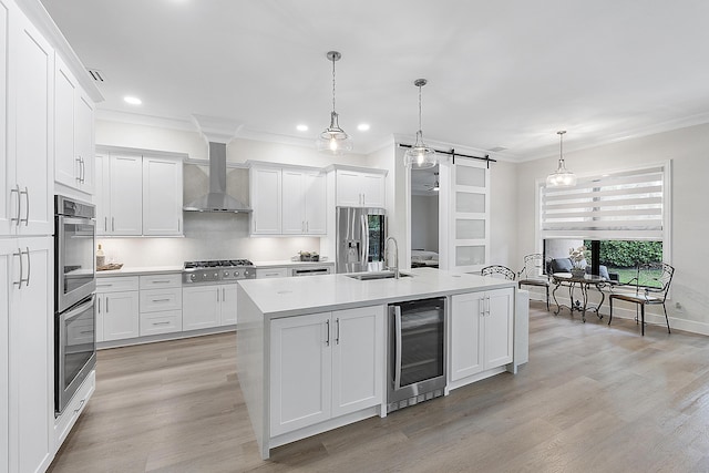 kitchen featuring beverage cooler, a barn door, stainless steel appliances, wall chimney exhaust hood, and a sink