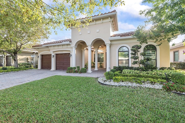 view of front of property with decorative driveway, a front lawn, an attached garage, and stucco siding