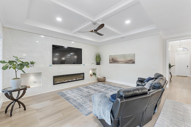 living room with light wood finished floors, a glass covered fireplace, coffered ceiling, and crown molding