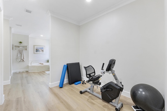 exercise area with visible vents, ornamental molding, baseboards, and wood finished floors