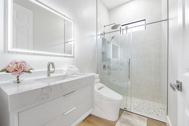 full bath featuring vanity, a shower stall, toilet, and wood finished floors