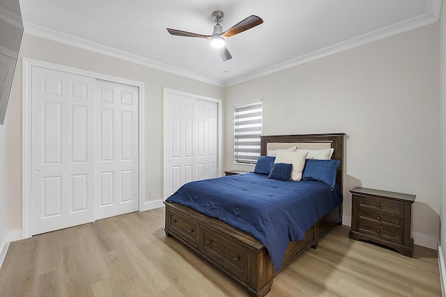 bedroom featuring crown molding, light wood-style flooring, baseboards, and two closets