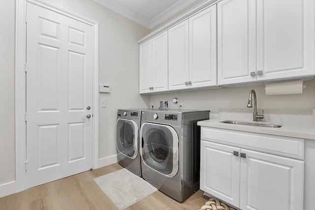 washroom featuring light wood-style flooring, a sink, washer and dryer, cabinet space, and crown molding