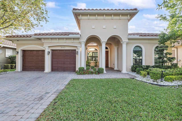 mediterranean / spanish-style house with stucco siding, decorative driveway, a front yard, and an attached garage