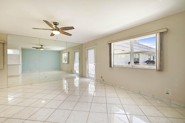 spare room with light tile patterned floors, ceiling fan, and a wealth of natural light