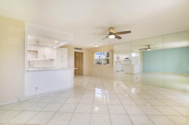 empty room featuring light tile patterned floors, baseboards, visible vents, a ceiling fan, and a sink