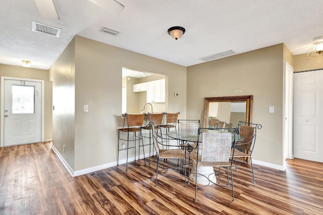 dining space with visible vents, baseboards, and wood finished floors