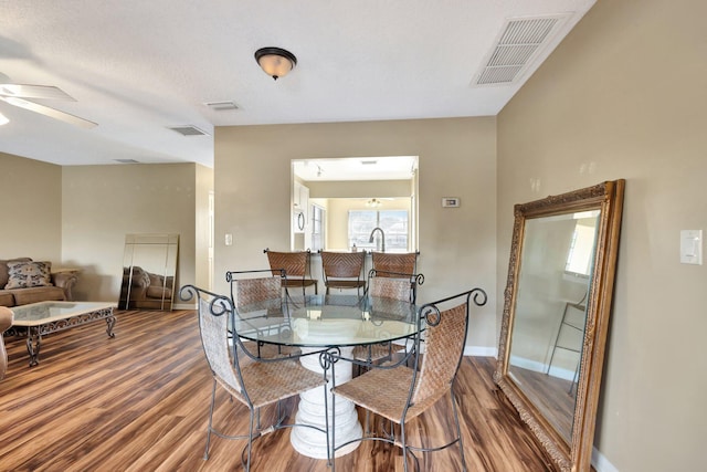 dining area with ceiling fan, visible vents, baseboards, and wood finished floors