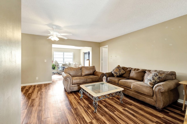 living area featuring a textured ceiling, baseboards, and wood finished floors