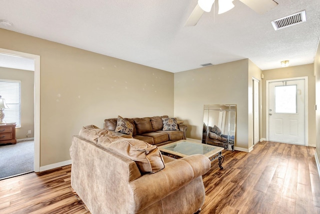 living area with visible vents, baseboards, and wood finished floors