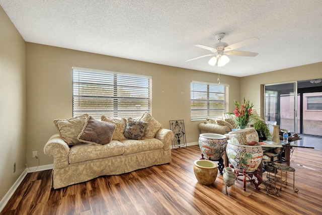 living area featuring wood finished floors, baseboards, and ceiling fan