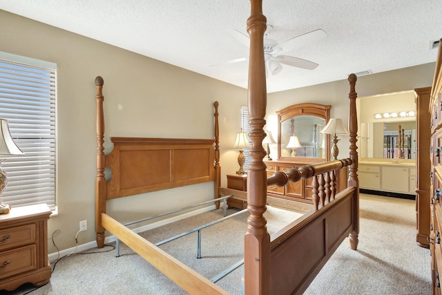 bedroom with baseboards, ceiling fan, ensuite bathroom, a textured ceiling, and light carpet