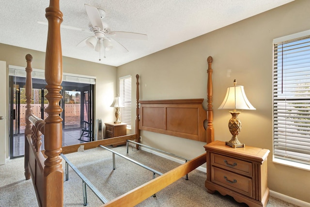 bedroom with light colored carpet, a textured ceiling, a ceiling fan, and multiple windows