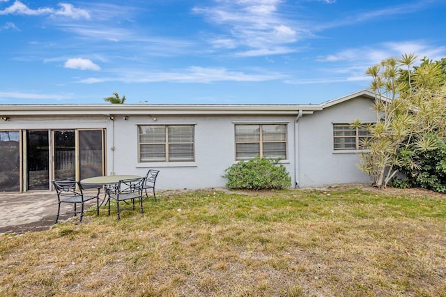 back of house featuring stucco siding, a patio, and a yard