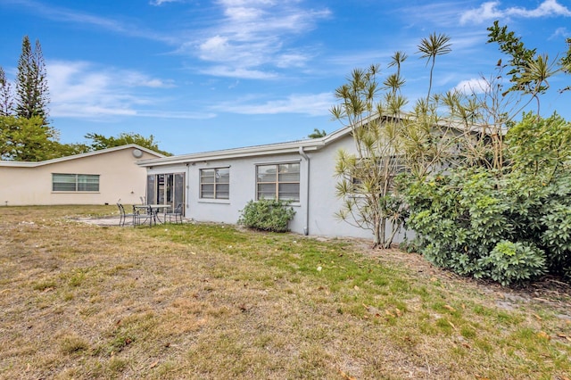 view of front of property featuring stucco siding, a patio, and a front lawn