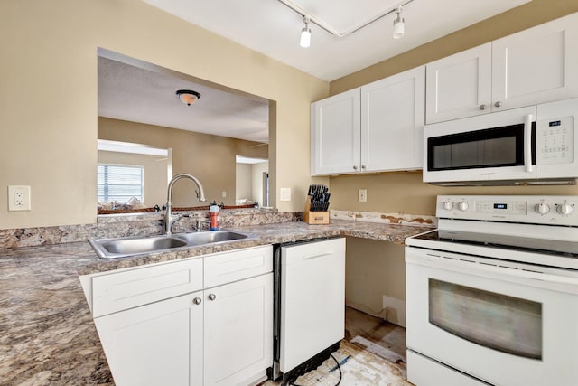 kitchen with white appliances, a sink, light countertops, rail lighting, and white cabinetry