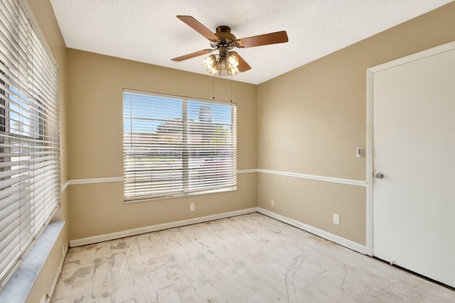 spare room with ceiling fan, wood finished floors, baseboards, and a textured ceiling