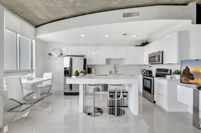 kitchen featuring a kitchen bar, stainless steel appliances, modern cabinets, and a sink