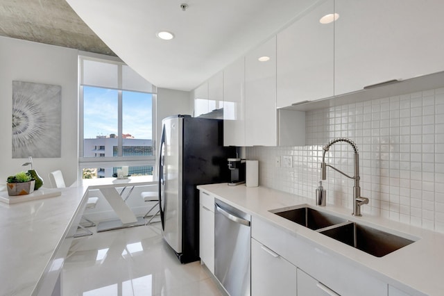 kitchen with a sink, tasteful backsplash, stainless steel dishwasher, and white cabinets