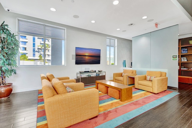 living room with recessed lighting, visible vents, baseboards, and wood finished floors