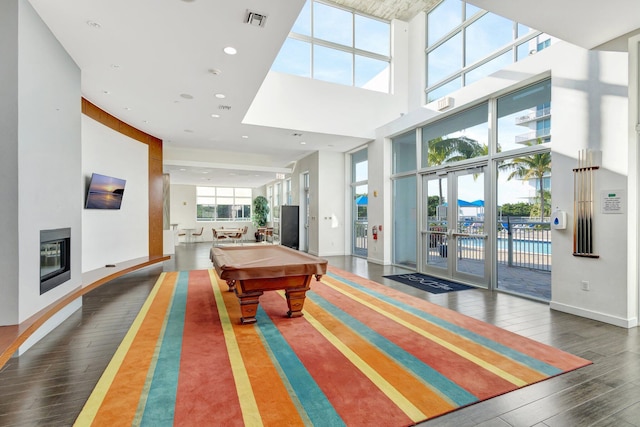 rec room with visible vents, pool table, a towering ceiling, a glass covered fireplace, and wood-type flooring