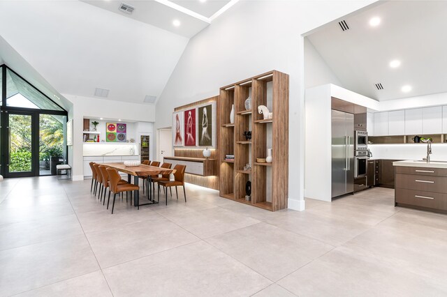 kitchen with built in appliances, high vaulted ceiling, light countertops, white cabinetry, and modern cabinets