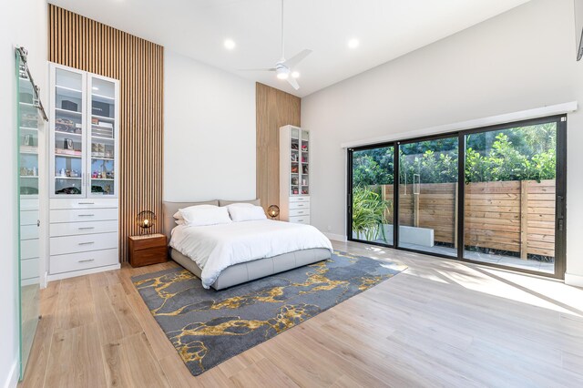 bedroom featuring access to exterior, a towering ceiling, and wood finished floors