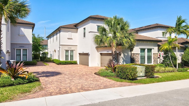 view of front of house with decorative driveway, a tile roof, stucco siding, and stone siding