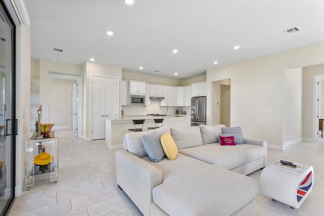 living room with light tile patterned floors, recessed lighting, and visible vents