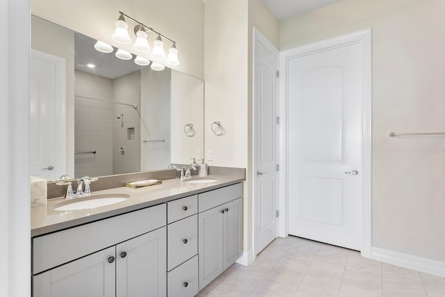 full bathroom with double vanity, tiled shower, tile patterned flooring, and a sink