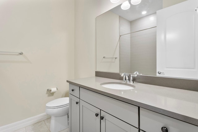 bathroom with toilet, vanity, baseboards, and tiled shower
