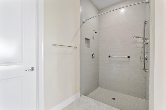 bathroom with tile patterned flooring, baseboards, and tiled shower