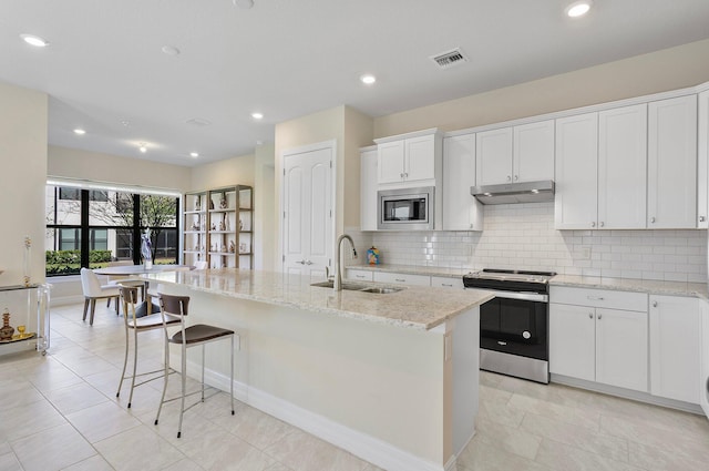 kitchen with decorative backsplash, visible vents, appliances with stainless steel finishes, under cabinet range hood, and a sink