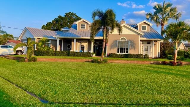 view of front of property featuring metal roof, a front lawn, a standing seam roof, and a chimney