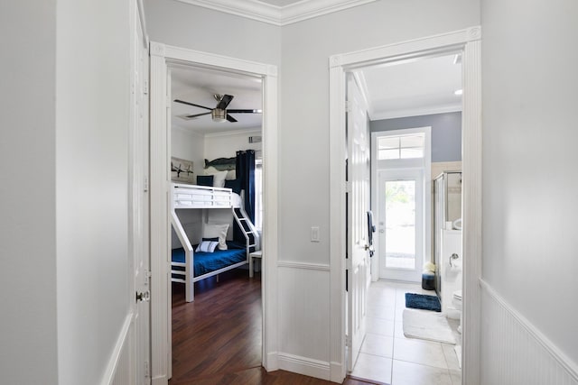 hall featuring a wainscoted wall, crown molding, and wood finished floors