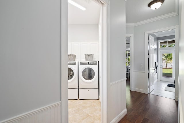 laundry room featuring a wainscoted wall, laundry area, wood finished floors, washer and dryer, and ornamental molding