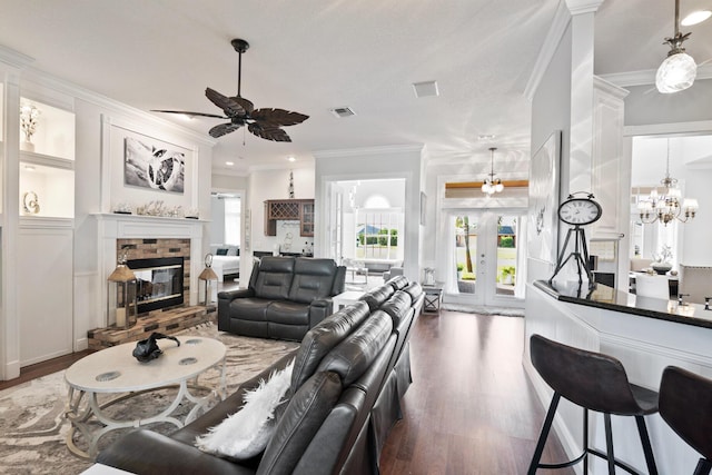 living room featuring a brick fireplace, visible vents, ornamental molding, and wood finished floors