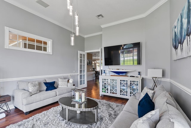 living room featuring baseboards, wood finished floors, visible vents, and crown molding