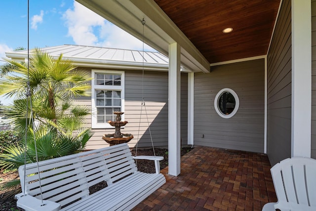 entrance to property featuring a standing seam roof, a patio area, and metal roof