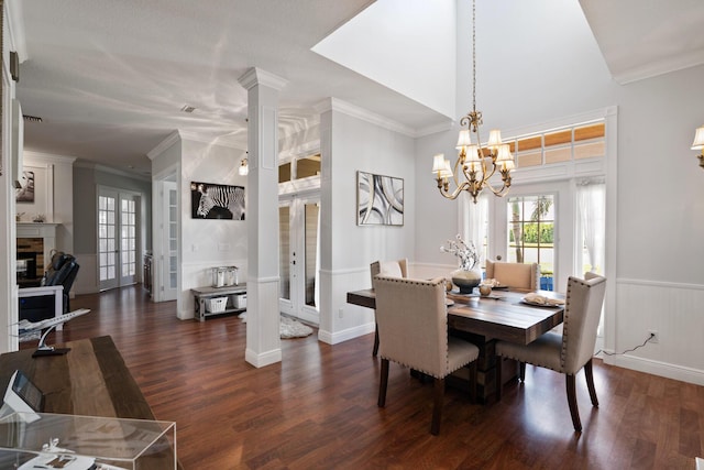 dining area featuring crown molding, a glass covered fireplace, dark wood-style flooring, and french doors