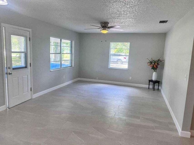 empty room featuring ceiling fan, baseboards, and a healthy amount of sunlight