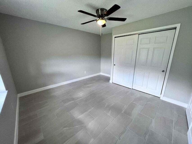 unfurnished bedroom featuring a closet, ceiling fan, a textured ceiling, and baseboards